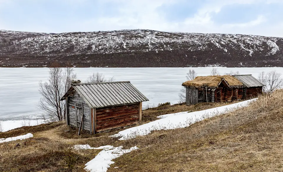 Kevättalvi Utsjoella: jäinen järvi ja vanhoja hirsirakennuksia